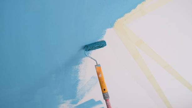 istock Decorator painting wall in blue color and using scotch tape 1412800343