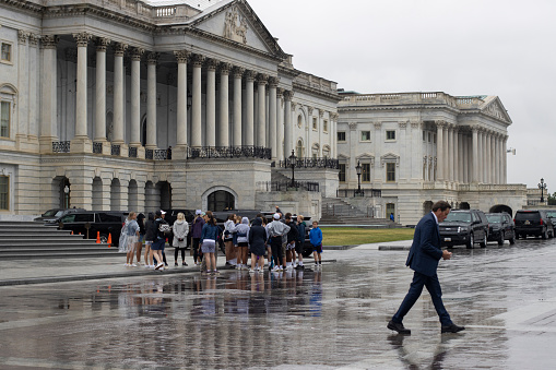 Washington, DC, USA - June 23, 2022: A group of visitors are seen outside the East Front of the United States Capitol Building in Washington, DC, on a rainy day.