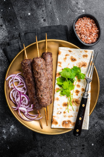 istock Lamb meat kofta kebab, onion and flat bread on plate. Black background. Top view 1412806982