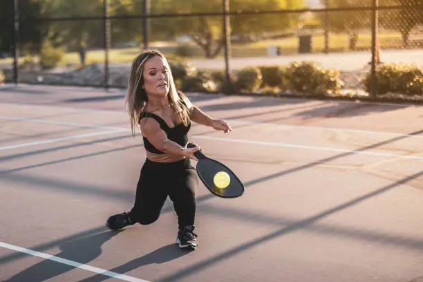 A beautiful woman with dwarfism playing pickle ball at the park and having fun.