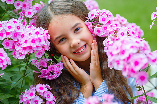 Madrid Spain. April 26, 2014. Close-up shot of Smiling young blonde girl looking at camera in natural environment surrounded by purple flowers