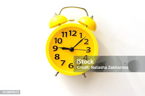 istock A yellow alarm clock lies on a white table, top view 1412809672