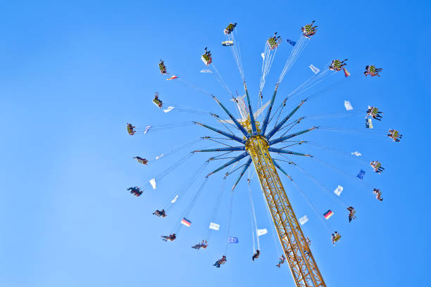 People riding a traditional Victorian chair-o-plane ride with the sun at Bournemouth seafront.