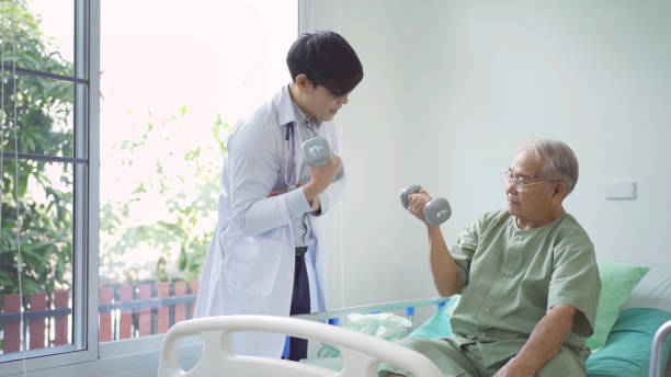 istock Happy old elderly Asian patient or pensioner and a doctor smiling, doing exercise, working out  in nursing home in hospital. Senior people lifestyle activity recreation. Health care physical therapy. 1412814692