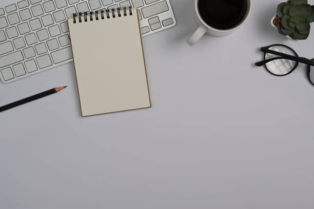 istock Top view notepad, coffee cup, eyeglasses and succulent plants on white office desk. 1412814812