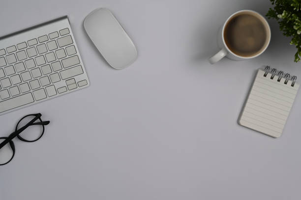istock White office desk with eyeglasses, keyboard, coffee cup and notebook. Top view with copy space. 1412814813