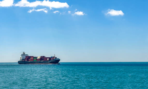 Side view of a long floating cargo ship loaded with many containers Ferry transportation concept. Cargo container freight shipment. Different cargo ship  traveling and connecting goods with countries. Nautical background with copy space floating platform stock pictures, royalty-free photos & images