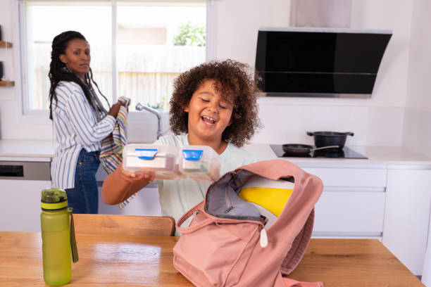 istock Happy elementary-age child putting a lunch box into a pink backpack before going to school. 1412817244