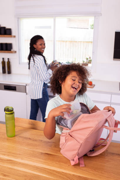 istock Happy elementary-age child putting a lunch box into a pink backpack before going to school. 1412817334
