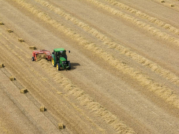 tracteur john deere ramassant des balles de paille vues d’en haut - organic horizon over land horizontal crop photos et images de collection