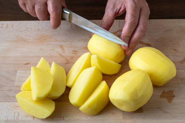 istock Hands with knife cutting potatoes, preparing potatoes for cooking. 1412821363