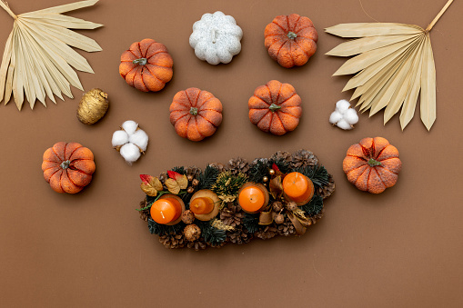 Autumn background decoration from dry leaves, candles and pumpkin on warm  brown background top view with copy space for autumn, fall, thanksgiving concept