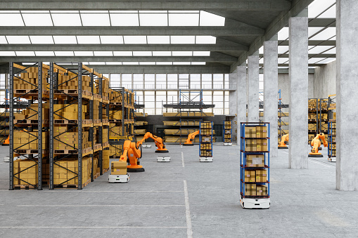 Distribution Warehouse With Automated Robots Putting Cardboard Box On AGV