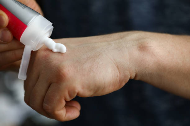 istock Man squeezes cream on his hand to moisturize skin 1412821900