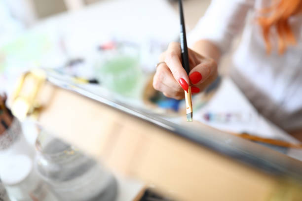 Close-up of artist painting new picture with oil paints. Talented woman using new technique. Paintbrush with paint. Creative process of painter at work. Art concept
