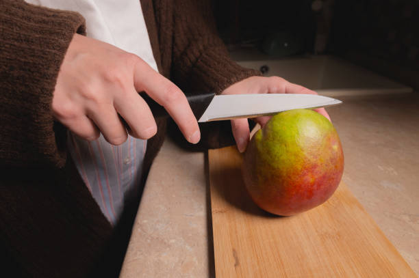 istock Top view woman cutting fruit on wooden board on table 1412823767