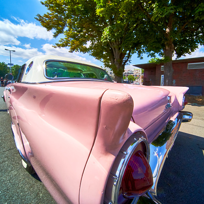 Wide angle view of the tail fin of a classic American road cruiser with light pink paint scheme
