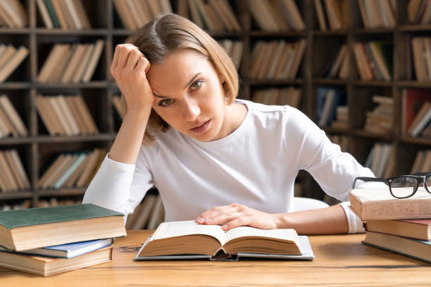 wyczerpana młoda kobieta z książkami studiująca w bibliotece. - student sleeping boredom college student zdjęcia i obrazy z banku zdjęć