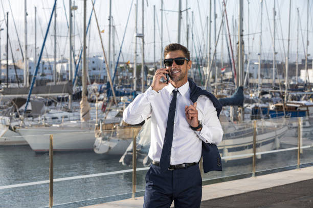 istock Happy businessman having smartphone conversation in harbor 1412825596