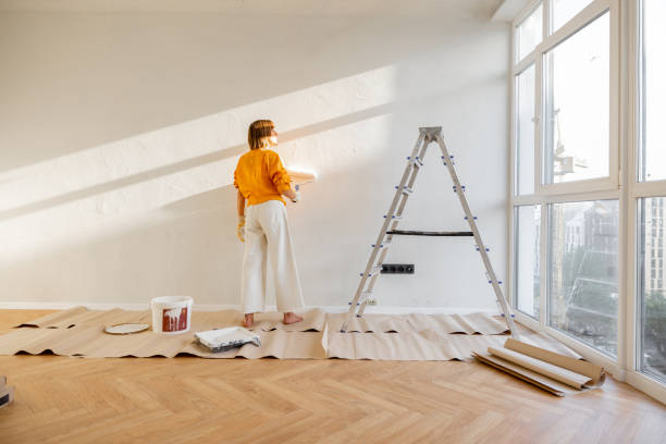 istock Woman paints wall, renovating her apartment 1412827654