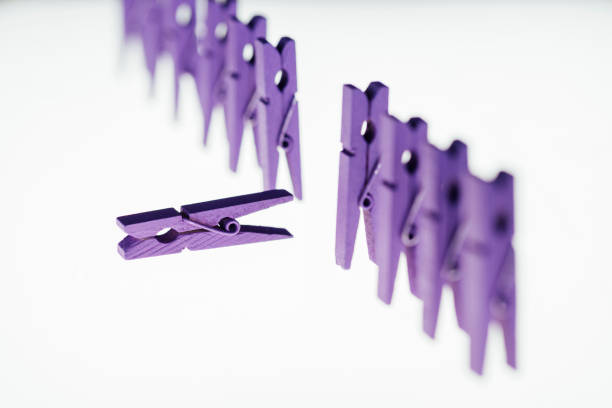 Clothespins in various colors are clipped onto a white clothesline, creating a vibrant display against a simple wall. The setting suggests a homey laundry area.