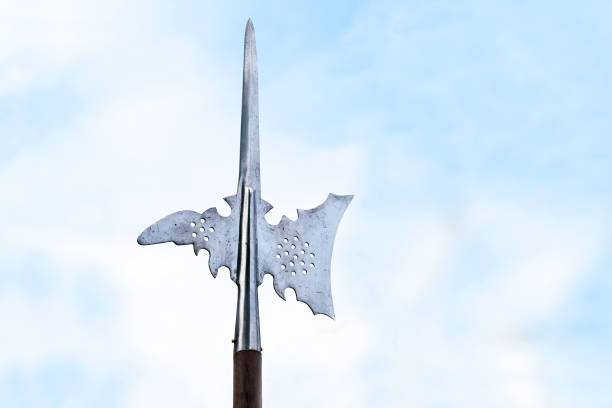 Metal top of a halberd, also called halbard, halbert or Swiss voulge, with axe blade and spike against a cloudy blue sky, pole weapon, copy space stock photo