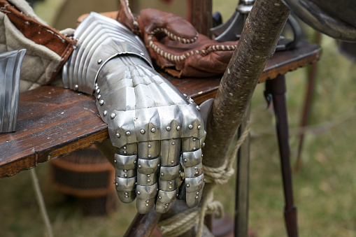 Protective gauntlet from metal plates as fully fingered glove, part of a historical knight armor replica at a medieval festival, copy space, selected focus, narrow depth of field