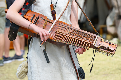 Nyckelharpa, keyed fiddle, a traditional Swedish musical instrument, string instrument or chordophone played by a young woman at a medieval festival, selected focus, narrow depth of field