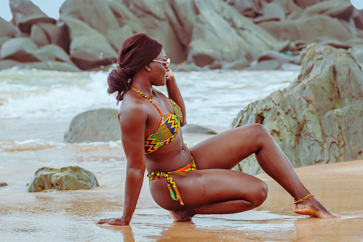 Africa Ghana woman enjoying on a beach in Axim Ghana West Africa with traditional african colors on swimwear and navel percing