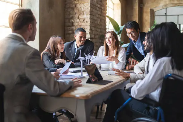 Photo of Group of multiethnic businesspeople discussing about financial strategy, renewable power, sustainable innovation project and environmental economical issues - business, sustainability interracial lifestyle concept