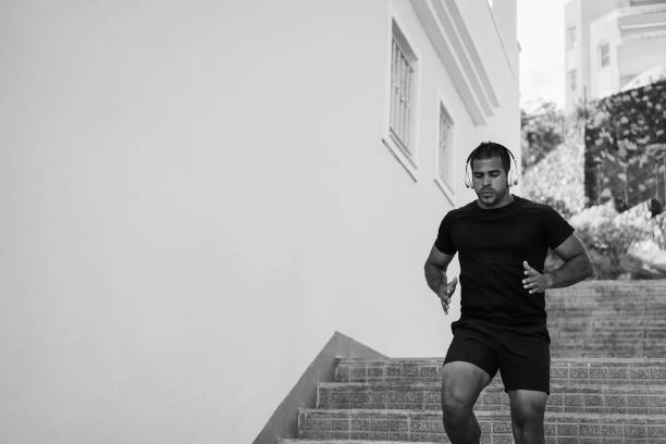 istock Fit hispanic man running outdoor - Focus on face - Black and white editing 1412836827