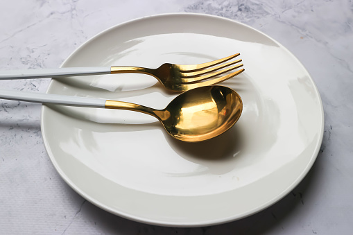 Spoon and fork on the white plate on the table