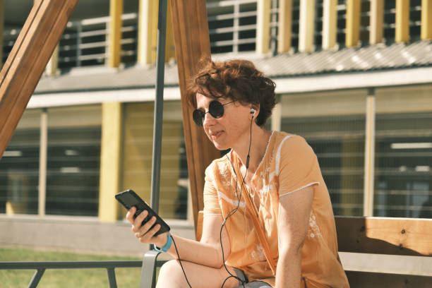 istock Woman is using phone and earbuds on the street 1412838688