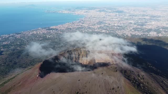 Aerial view of volcano Mount Vesuvius, volcanic terrain inside crater on top of mountain - panorama of Naples from above, Italy, Europe. Epic reveal. Drone footage 4K. Cloud over volcano. Vesuvio.