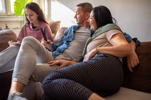 istock Family with one child relaxing at home and using technology 1412841537