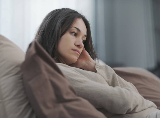 Sad young woman alone at home stock photo