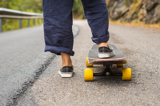 feet of a girl on a skateboard on a road