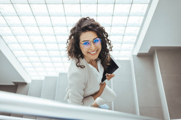 istock Businesswoman walking upstairs and using touchpad. 1412849127