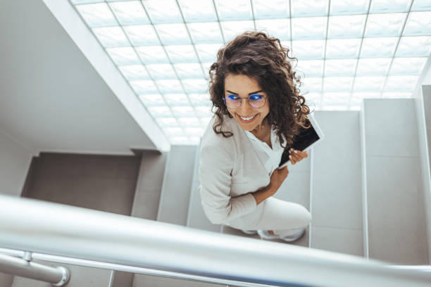 istock Businesswoman walking upstairs and using touchpad. 1412849128