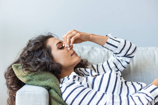 Upset depressed young woman lying on couch feeling strong headache migraine stock photo