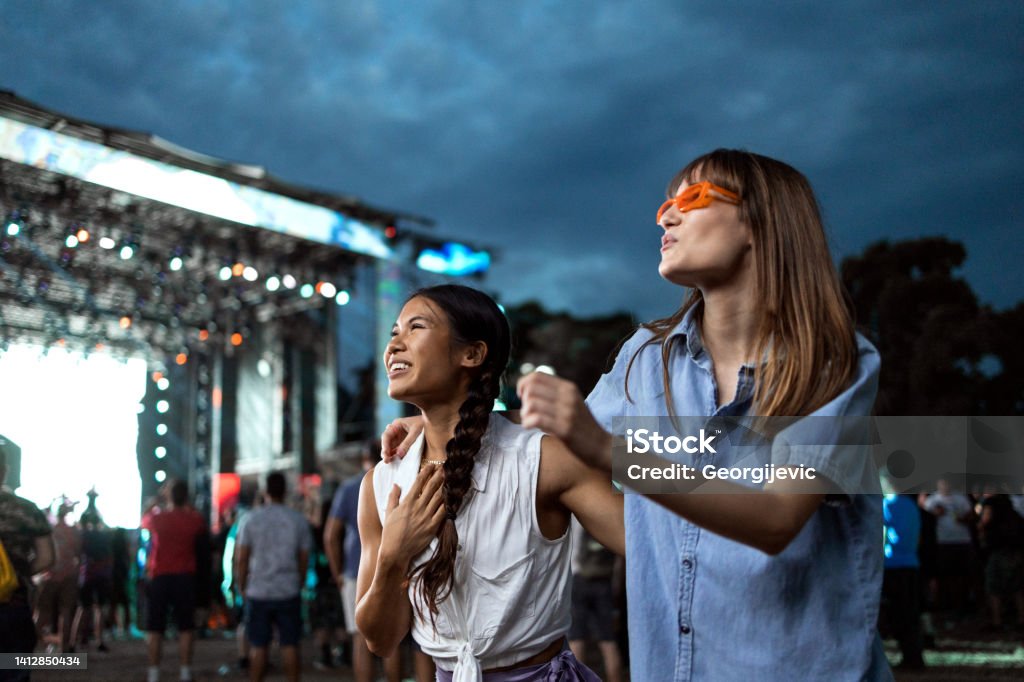 Music festival Two Asian and Caucasian girls dance in front of a stage and enjoy the atmosphere at a music festival. Music Festival Stock Photo