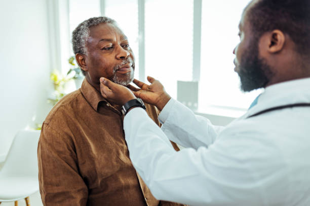 médico que realiza un examen de garganta en un hombre mayor - touching neck fotografías e imágenes de stock