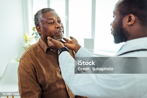 istock Doctor doing throat examination on older man 1412852006