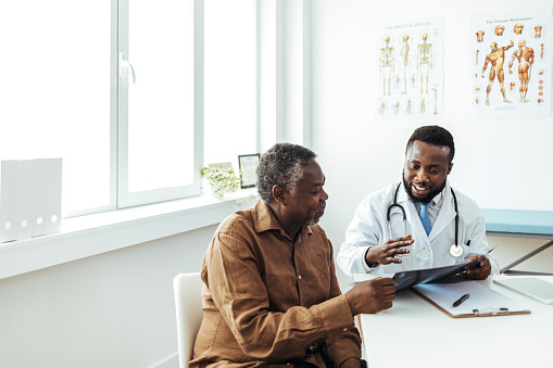 Orthopedic surgeons examine a patient's x-ray. A male doctor is holding the x-ray image.