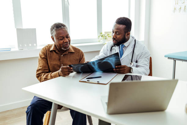 doctor smiling and giving good news to patient, showing him lung x-ray - medical exam doctor patient adult imagens e fotografias de stock