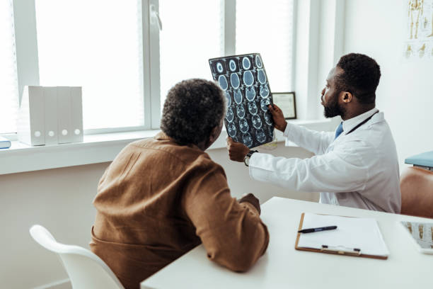 Do you have any questions so far? Male doctor and senior patient discussing brain scan results at the office. neurosurgery stock pictures, royalty-free photos & images