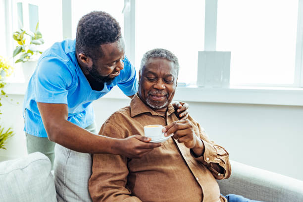 istock Nurse with senior man helping with coffee. 1412852643