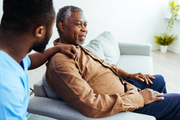 Social worker is visiting a senior man Caregiver consoling a senior male patient in a nursing home during the day. alzheimer's disease stock pictures, royalty-free photos & images
