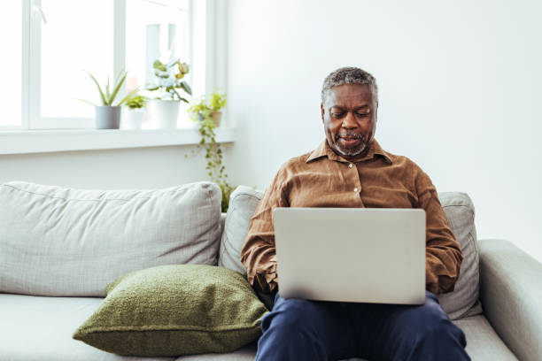 starszy mężczyzna pracujący na laptopie w domu - senior adult computer men mature adult zdjęcia i obrazy z banku zdjęć