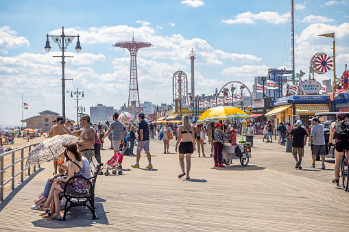 Coney Island, Brooklyn, NY, USA - June 25, 2022: View down the famous boardwalk on a hot and busy summerday